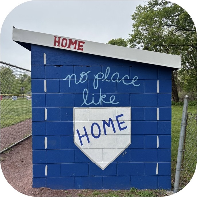 Dugout mural reading no place like HOME above a painted home plate on a royal blue wall