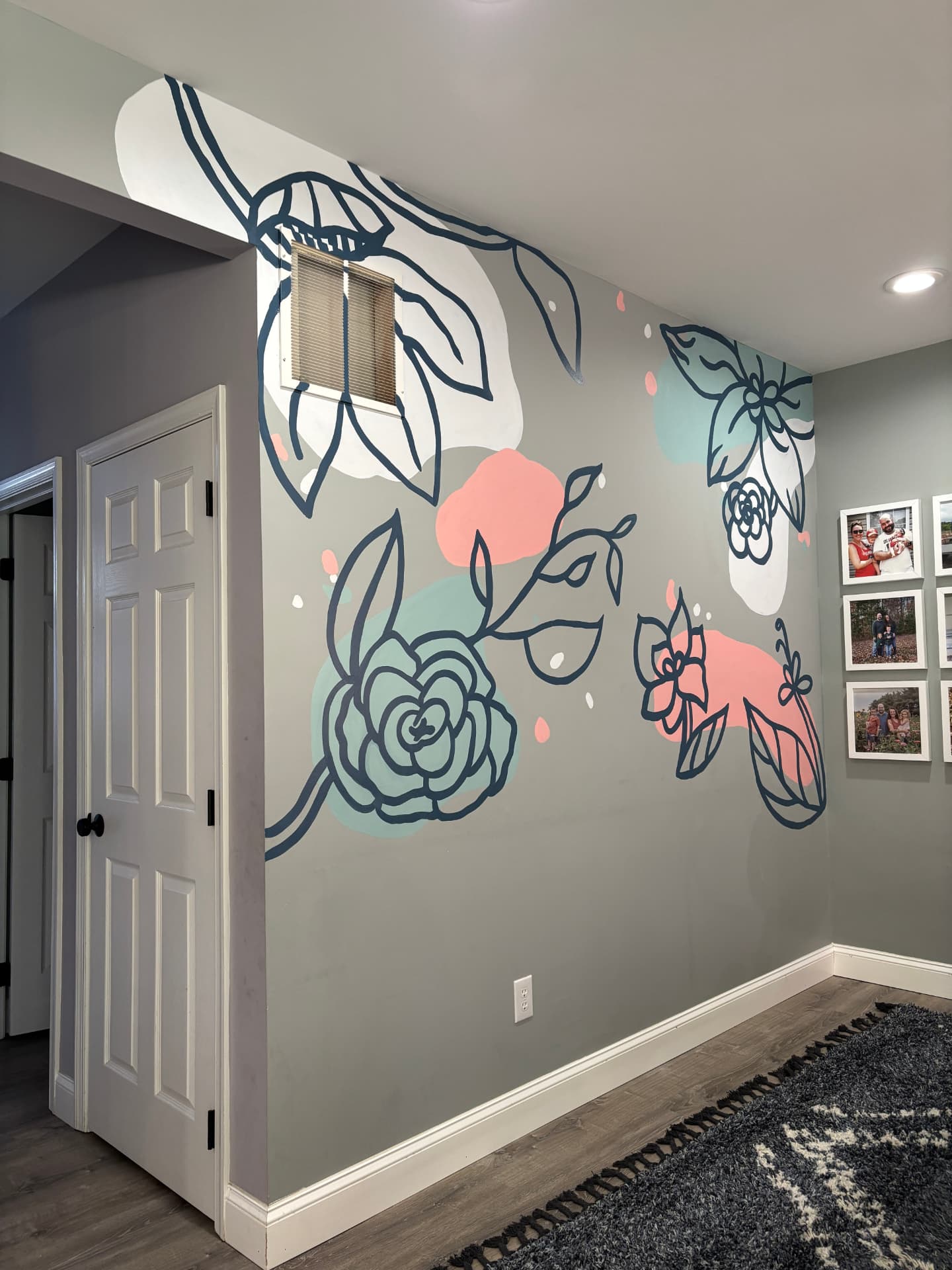 Interior wall mural of large stylized flowers and leaves in navy, coral and mint on a soft gray wall