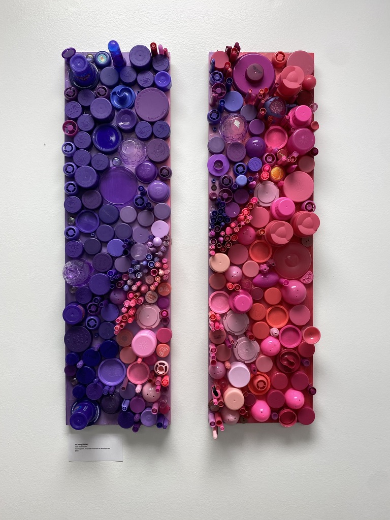 Two tall panels densely covered in sorted bottle caps, one in purples and one in pinks and reds