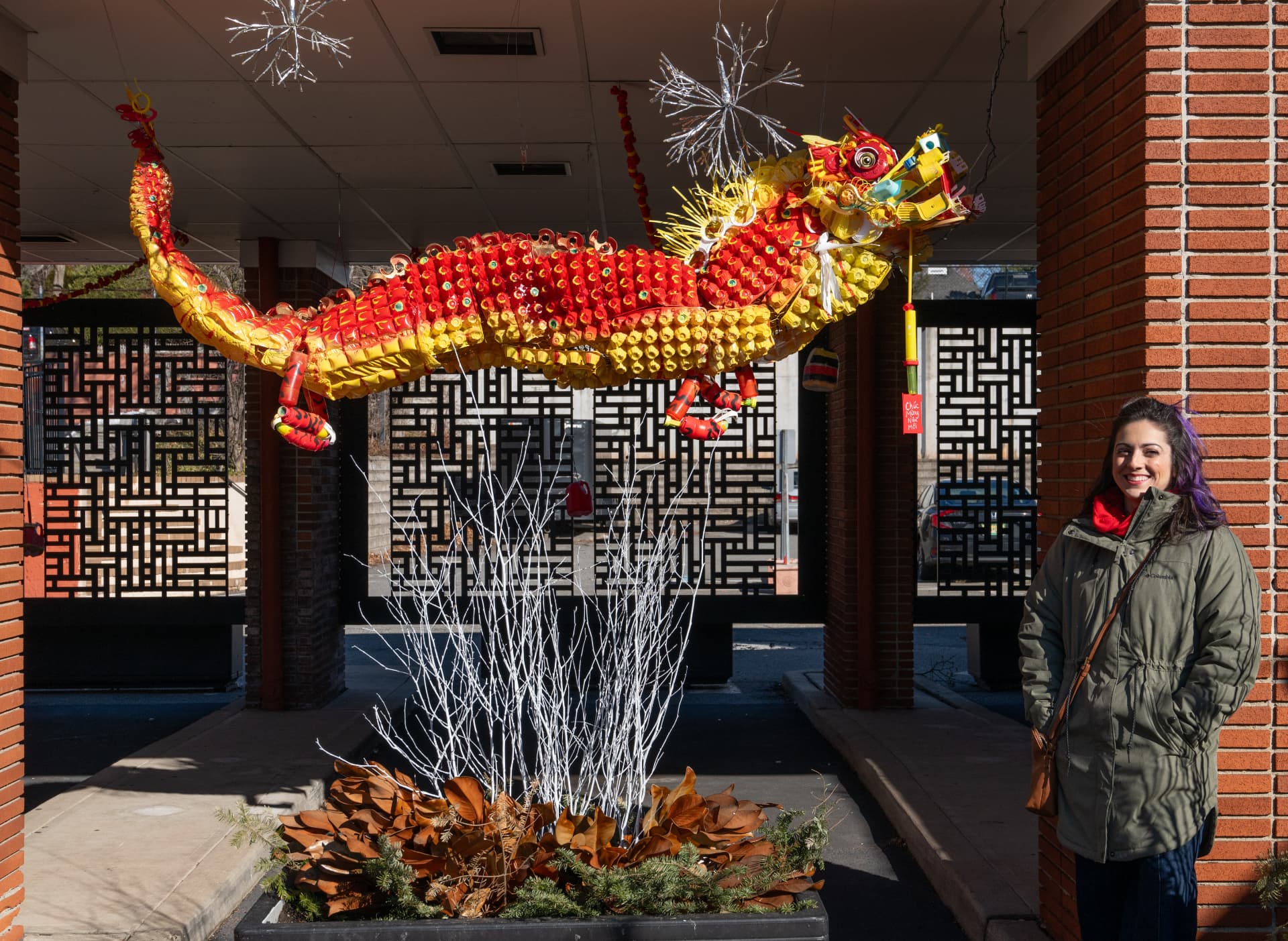 Large suspended dragon sculpture made from reused egg cartons and mixed materials on chicken wire for a Lunar New Year celebration