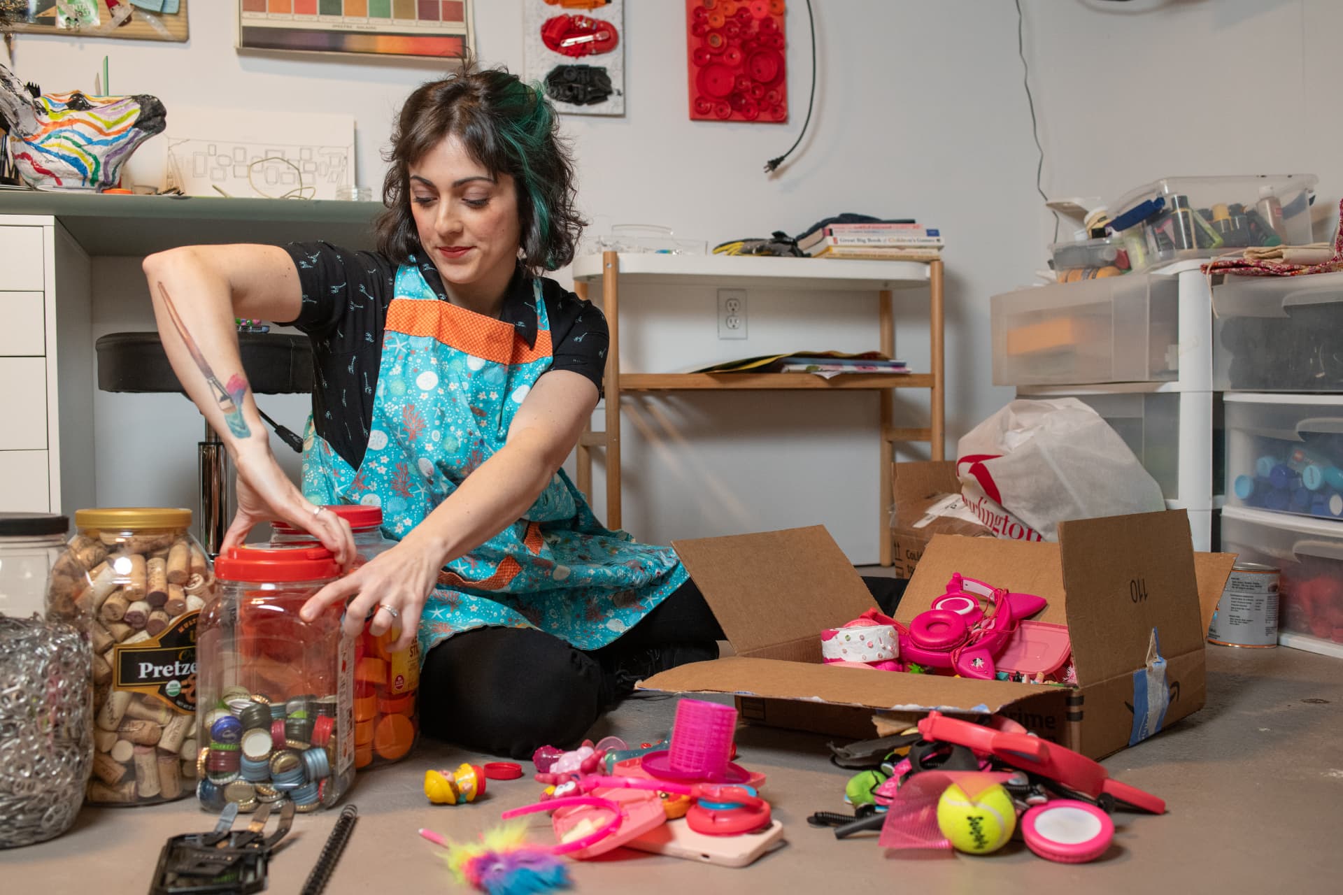 Julia sorting bottle caps, corks and reclaimed toys into jars on her studio floor